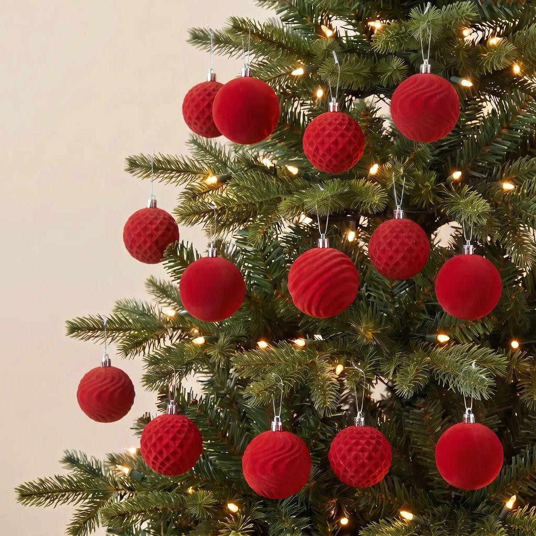 Red Velvet Christmas tree Bauble ornaments hanging on a green artificial Christmas tree with warm white string lights.
