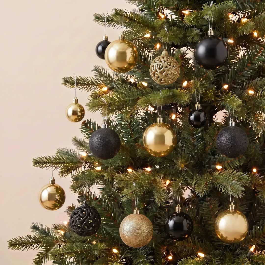 A boxed set of 100pcs black and gold plastic Christmas baubles featuring stunning glossy and glitter finishes.