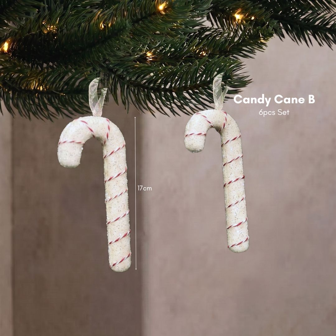 Close-up of a sweet pastel candy cane Christmas tree ornament hanging delicately on dark green pine branches.