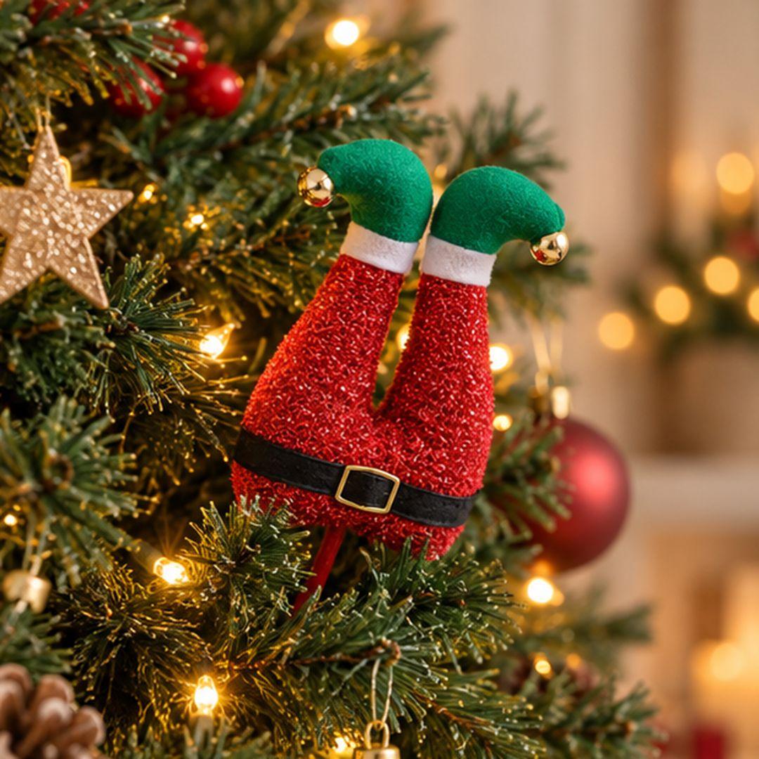 Red and green Christmas elf legs tree pick with glittery red outfit, black belt and green shoes inserted into an artificial Christmas tree.
