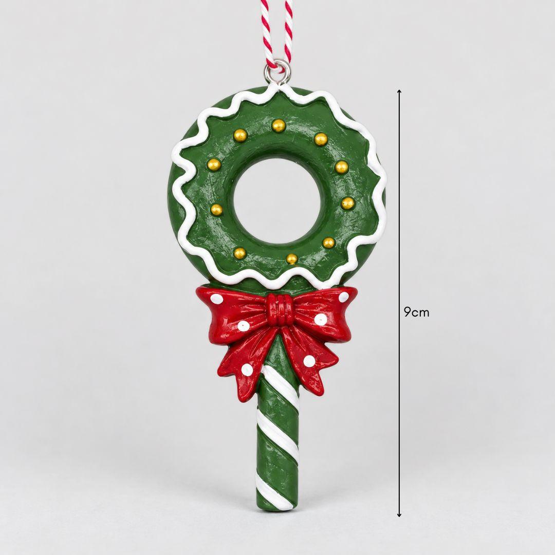 Little Joy red and green candy wreath lollipop resin Christmas ornaments with striped handles and festive bows hanging on a warm-lit Christmas tree.