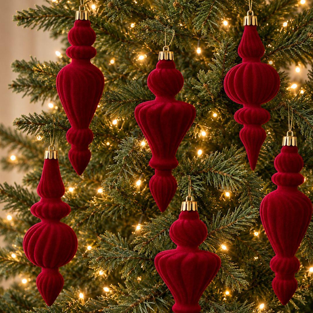 Ralph 16cm burgundy red velvet Christmas finial ornaments with sculpted ribbed textures and gold caps hanging on a warm-lit artificial Christmas tree.