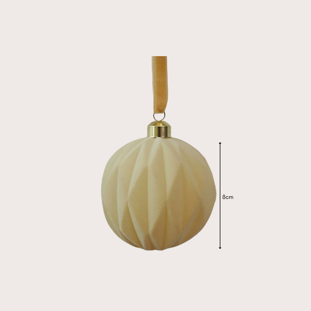 Ralph Heritage 8cm red and ivory velvet Christmas baubles with sculpted geometric patterns hanging on a warm-lit Christmas tree.