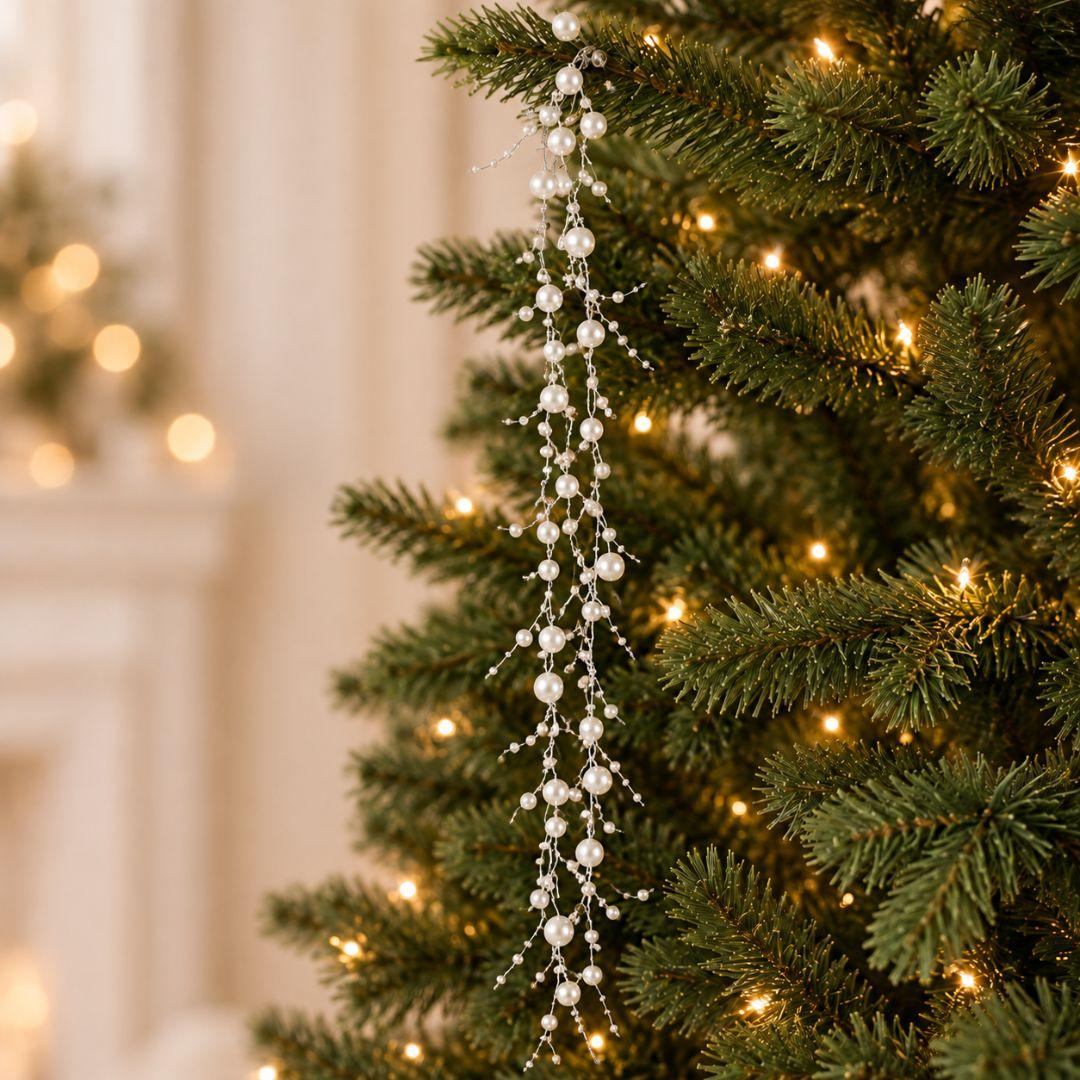 White pearl-effect beaded Christmas garland with assorted 0.3cm–0.8cm beads cascading from a warm-lit artificial Christmas tree.