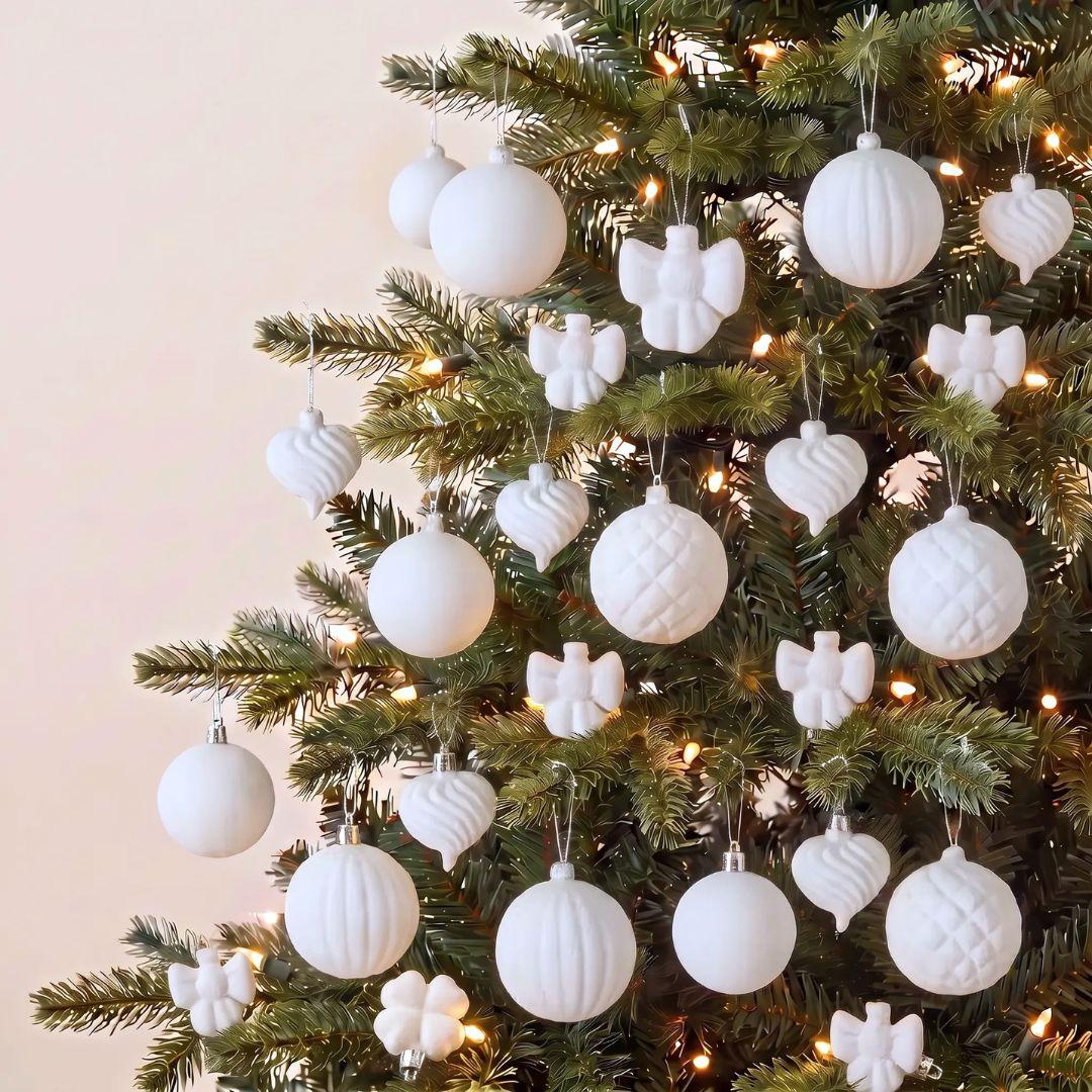 White Velvet decorative Christmas tree ornaments hanging on a green artificial tree with warm white string lights 