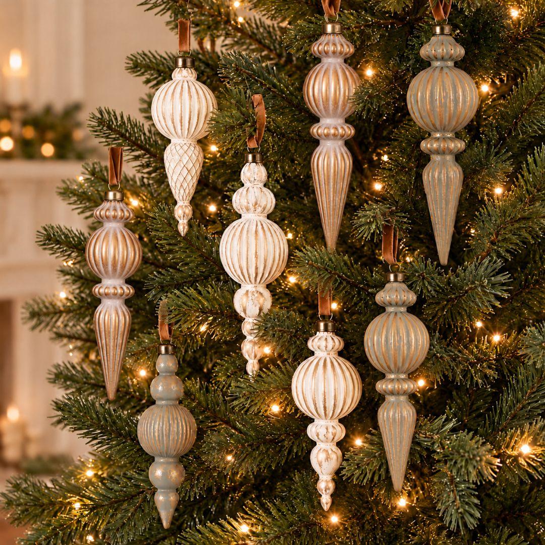 Set of 9 Aurelia vintage 16cm Christmas finial ornaments in ivory, champagne gold and sage with antique gold detailing hanging on a pre-lit Christmas tree.
