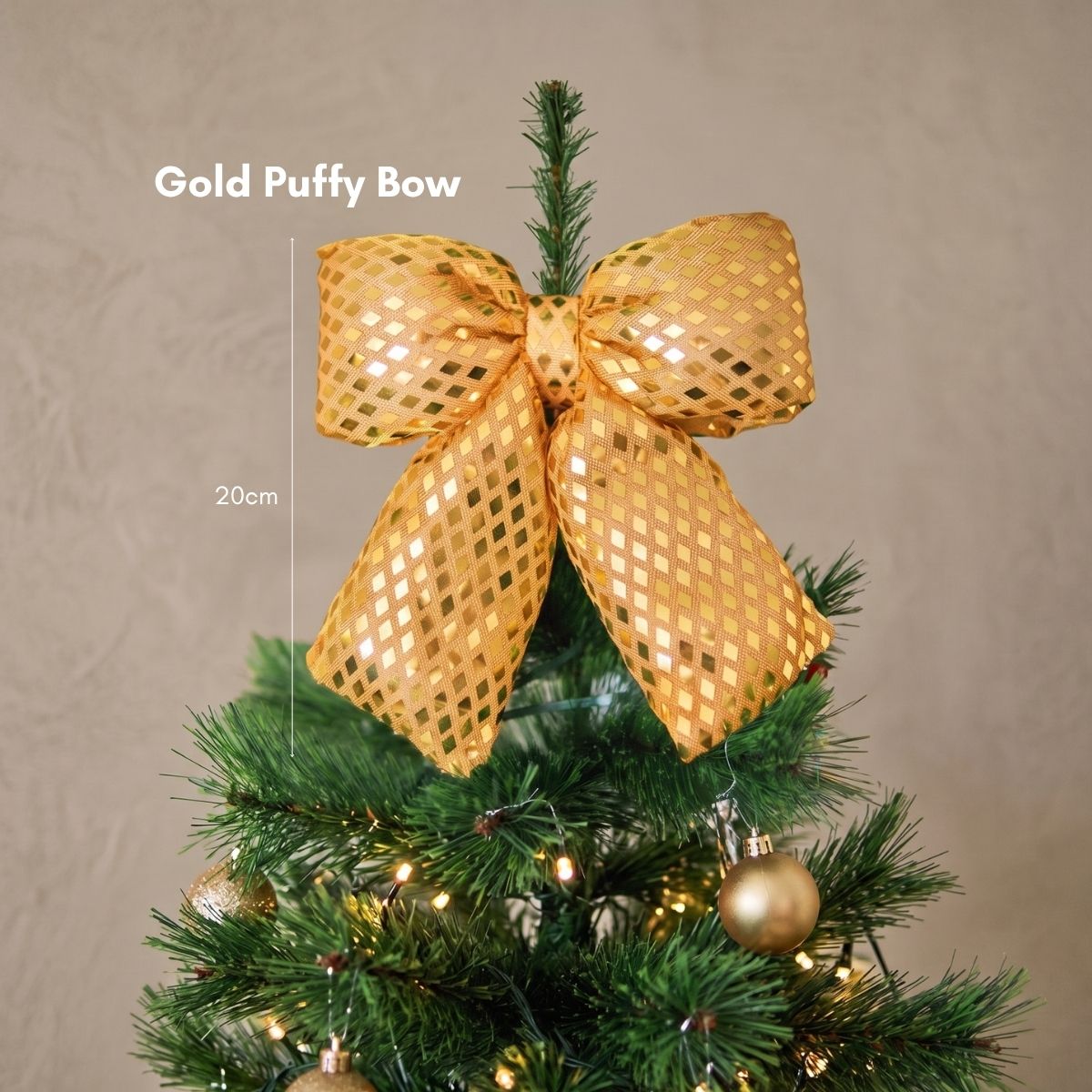 Close-up of a plush gold puffy bow Christmas tree ornament catching the warm light on dark green pine branches.