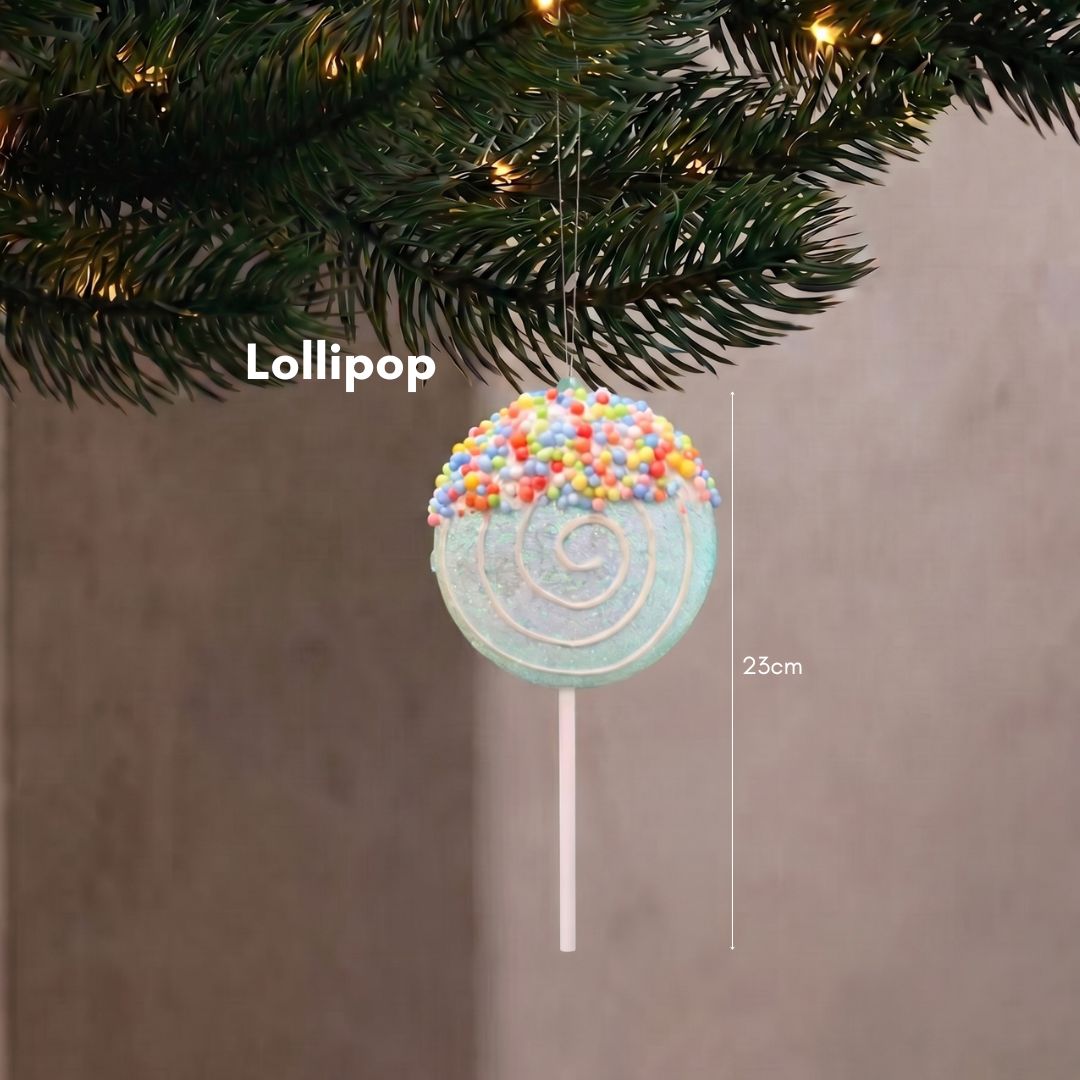Close-up of a sweet pastel lollipop Christmas tree ornament with a white icing swirl hanging delicately on dark pine branches.