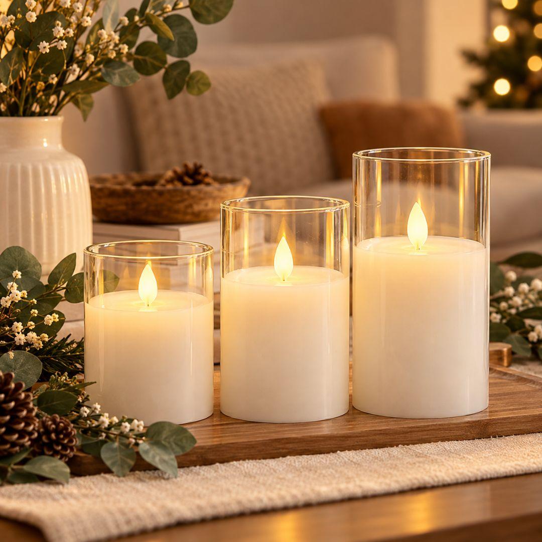 Three flameless LED glass candles in different sizes with warm flickering lights, styled on a wooden tray in a cosy minimalist living room.