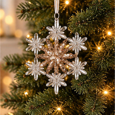 Gold and clear acrylic floral snowflake Christmas ornament with six decorative points and sparkling gold details hanging on an artificial Christmas tree.