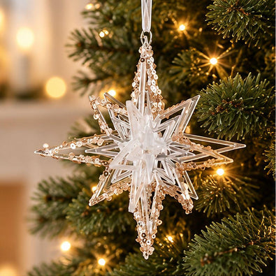 Gold and clear acrylic geometric Christmas star ornament with intricate layered points and sparkling gold details hanging on a lit Christmas tree.