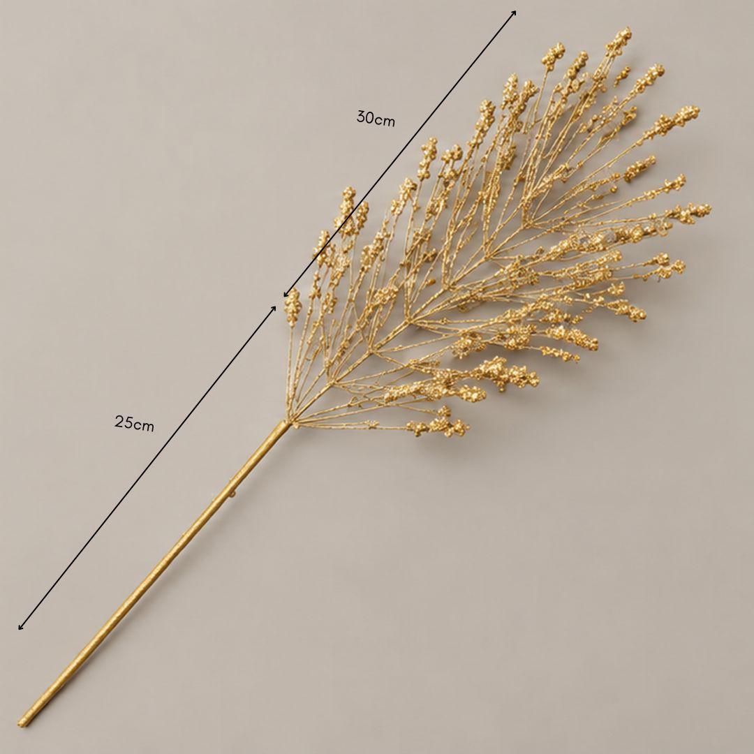 Gold glitter branch Christmas tree pick with delicate fan-shaped branches and sparkling gold accents displayed on a warm-lit artificial Christmas tree.
