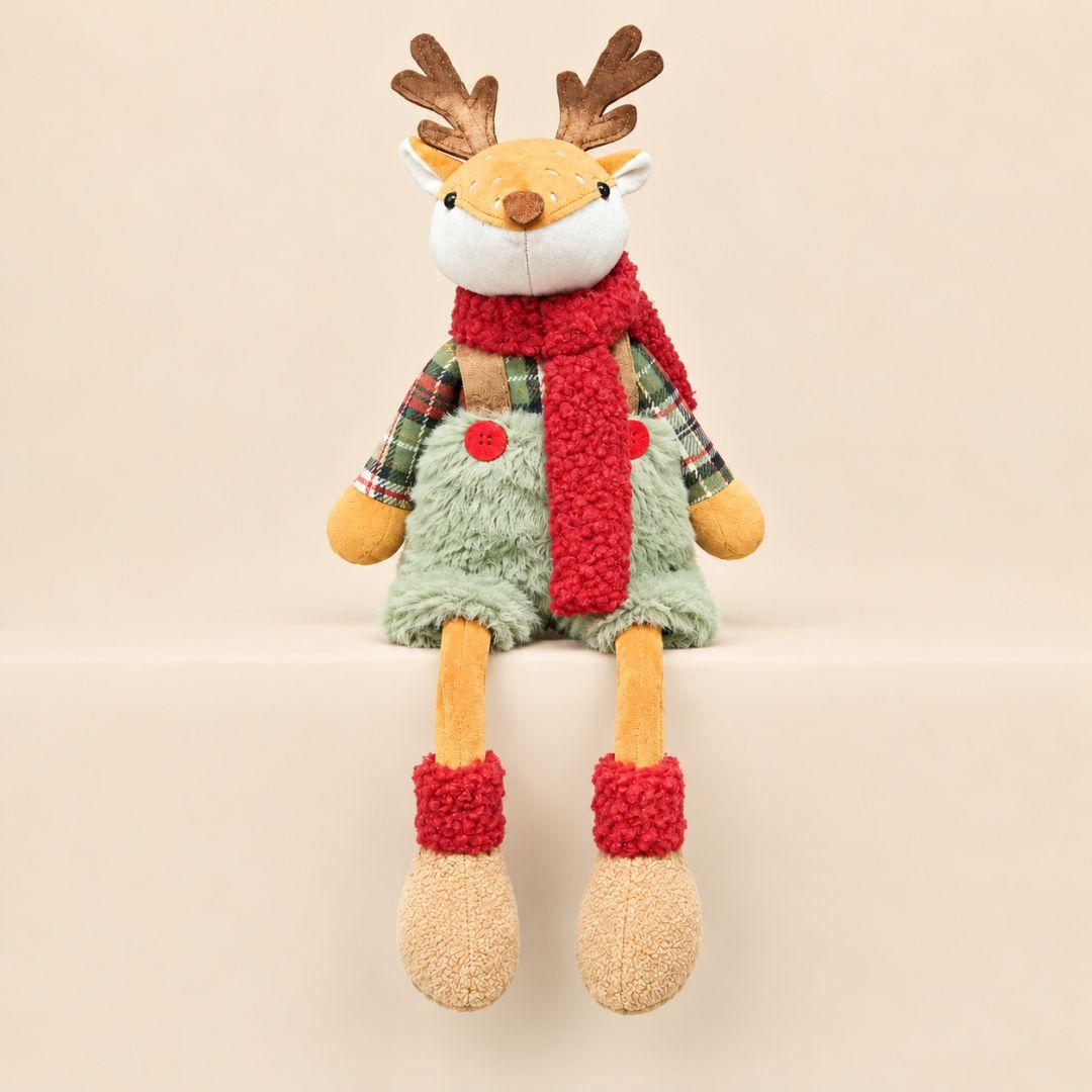 Holly and Hazel sitting Christmas reindeer plush decorations with dangling legs on a wooden table in a festive living room 