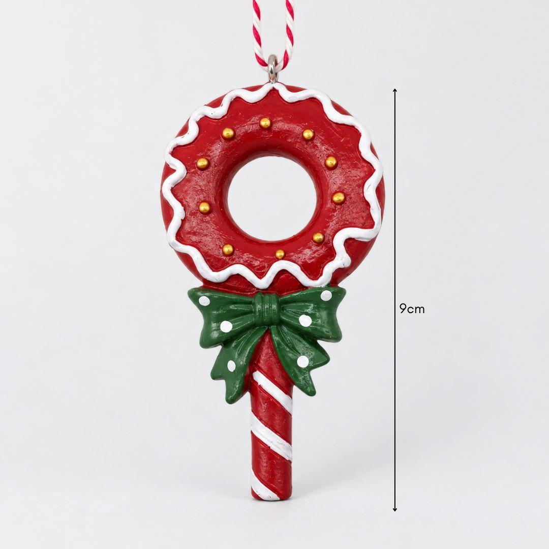 Little Joy red and green candy wreath lollipop resin Christmas ornaments with striped handles and festive bows hanging on a warm-lit Christmas tree.