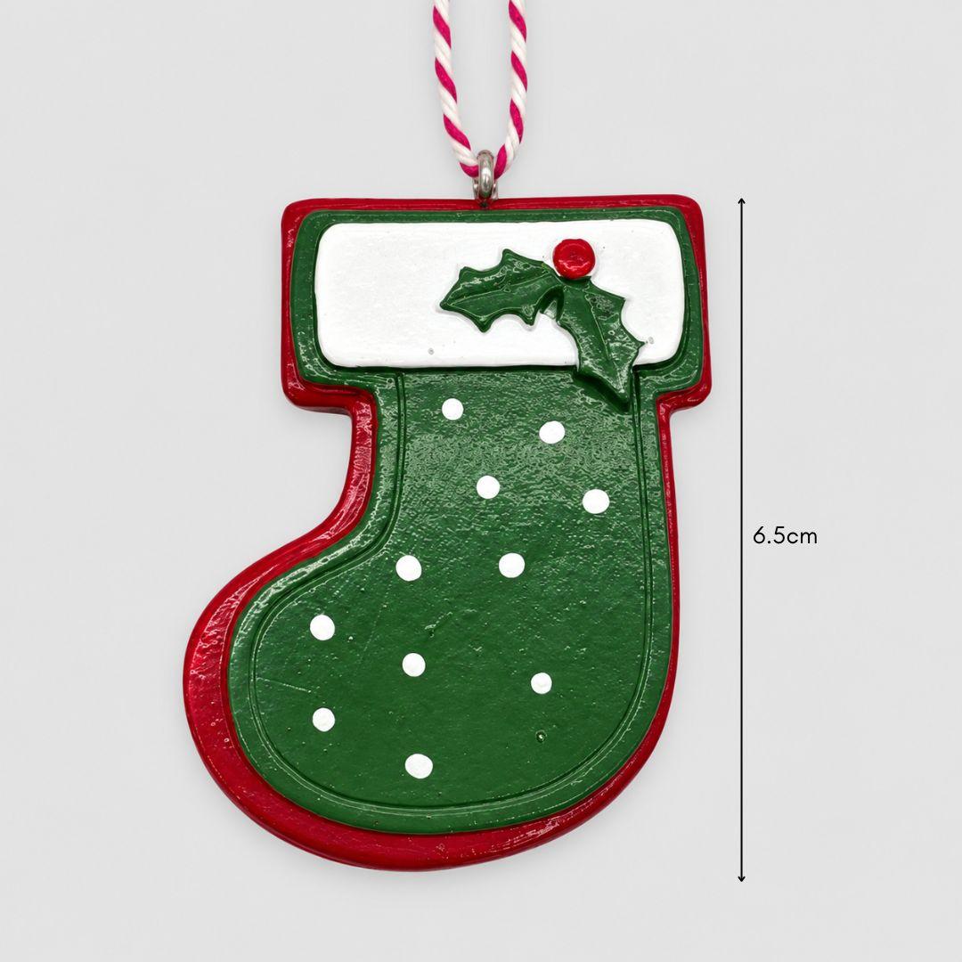 Little Joy red and green miniature Christmas stocking resin ornaments with white polka dots, snowy cuffs and holly accents hanging on a Christmas tree.