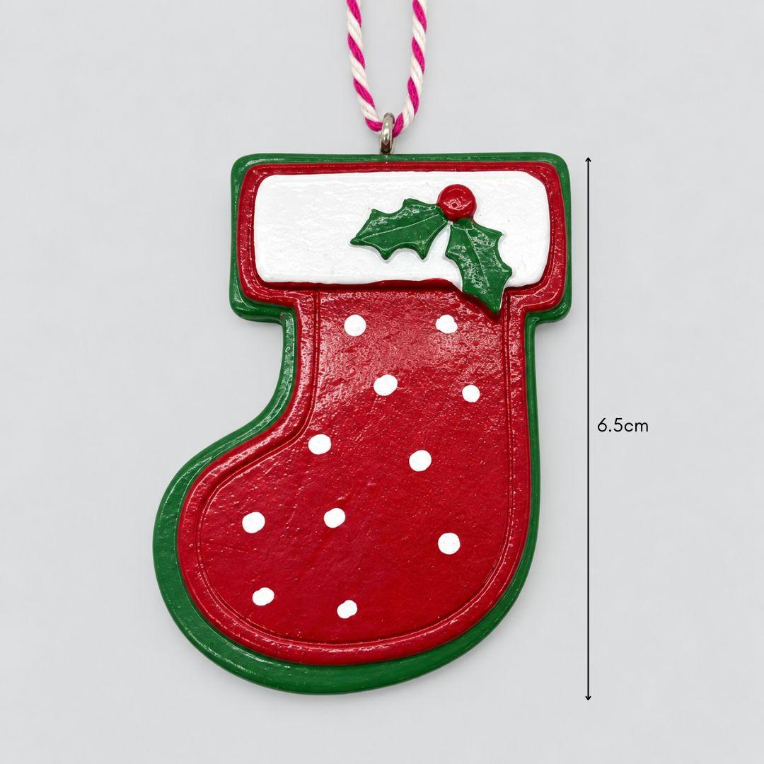 Little Joy red and green miniature Christmas stocking resin ornaments with white polka dots, snowy cuffs and holly accents hanging on a Christmas tree.