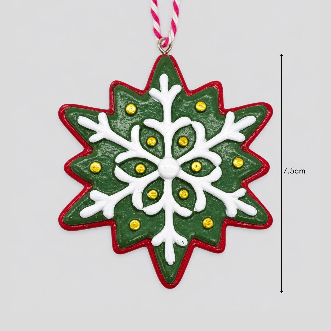 Little Joy red and green resin snowflake Christmas ornaments featuring raised white icing-inspired patterns on an artificial Christmas tree.