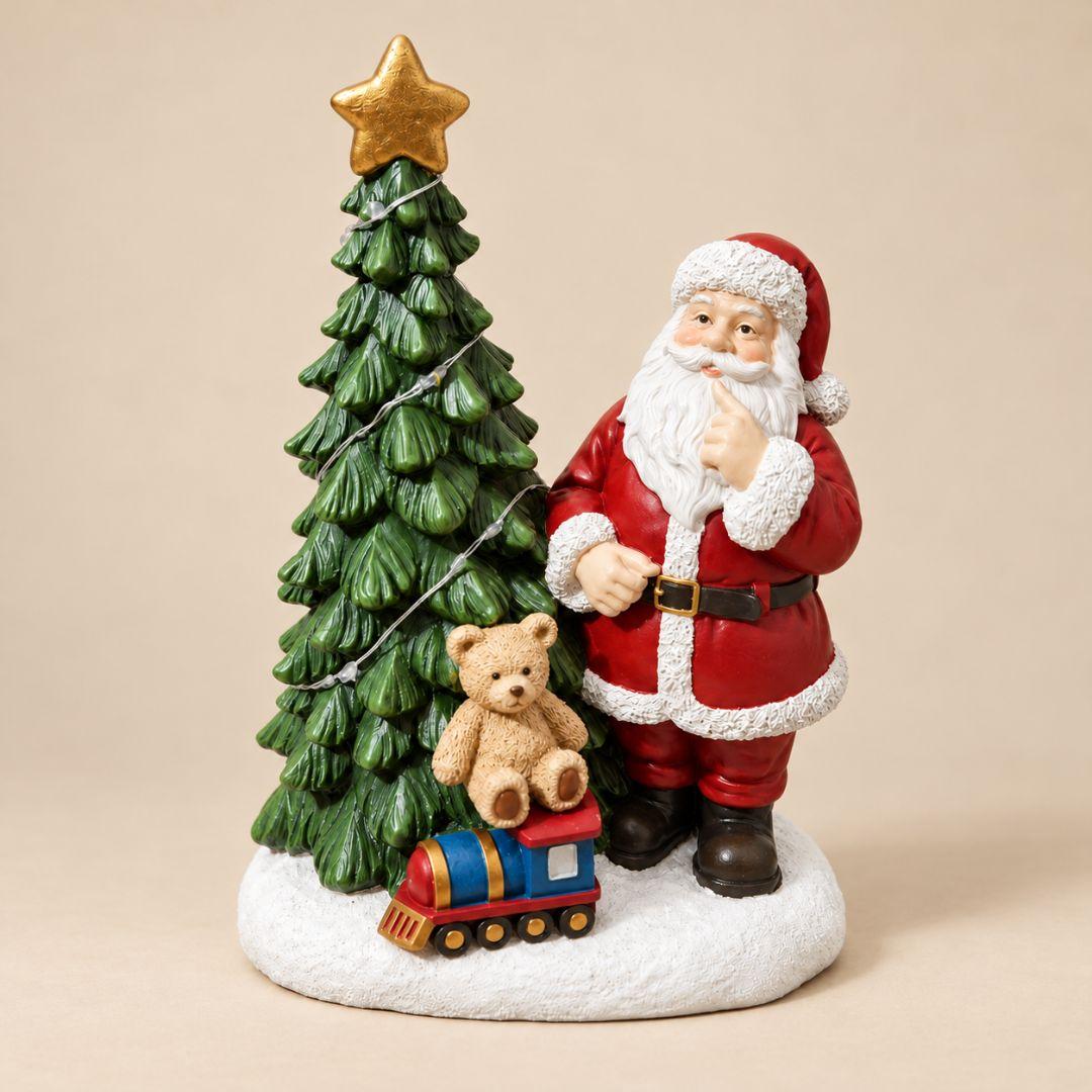 Santa's Toyland Christmas figurine with Santa Claus beside a green Christmas tree, miniature teddy bear and colourful toy train on beige background
