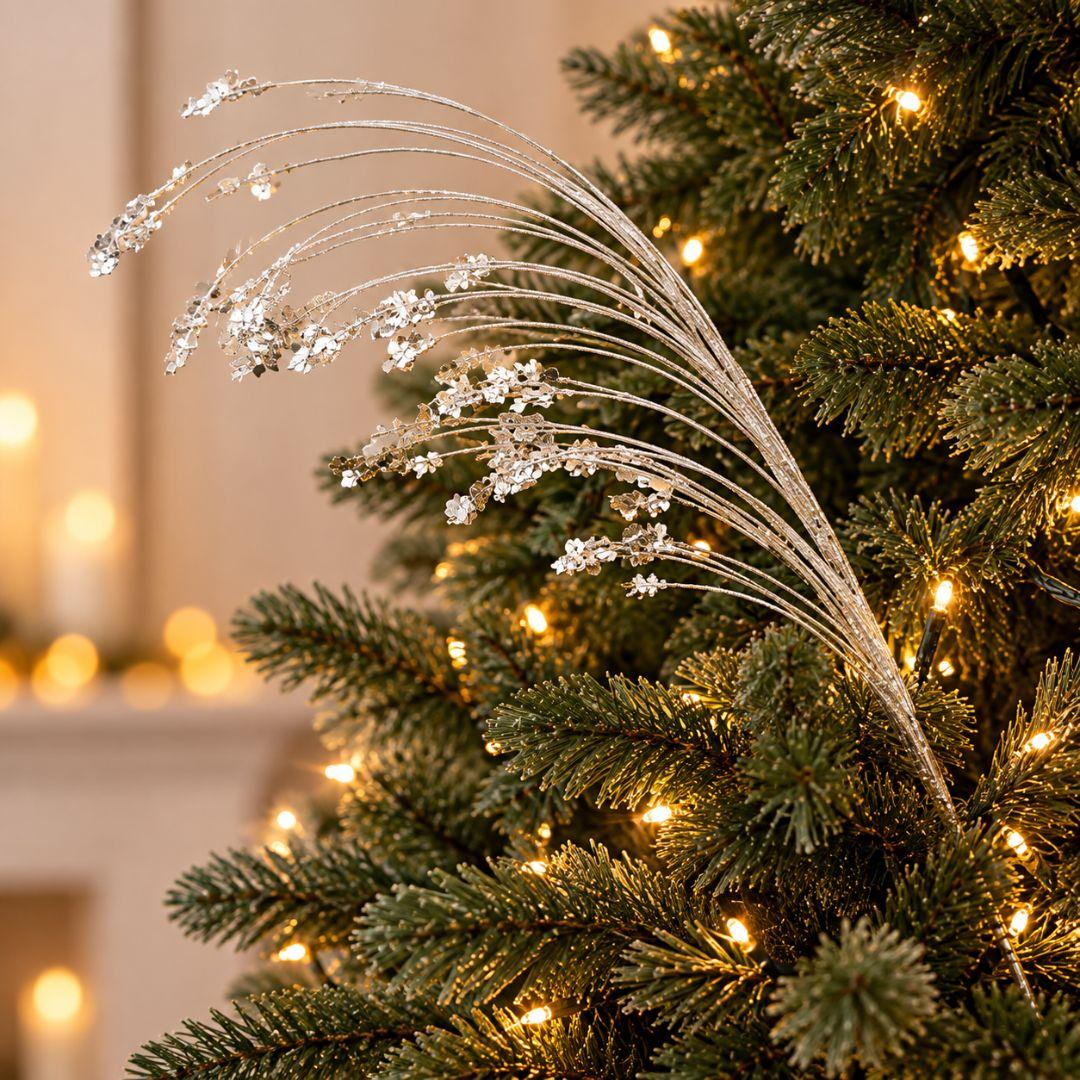 Silver glitter and sequin Christmas tree pick featuring delicate cascading branches and shimmering silver accents on a warm-lit Christmas tree.