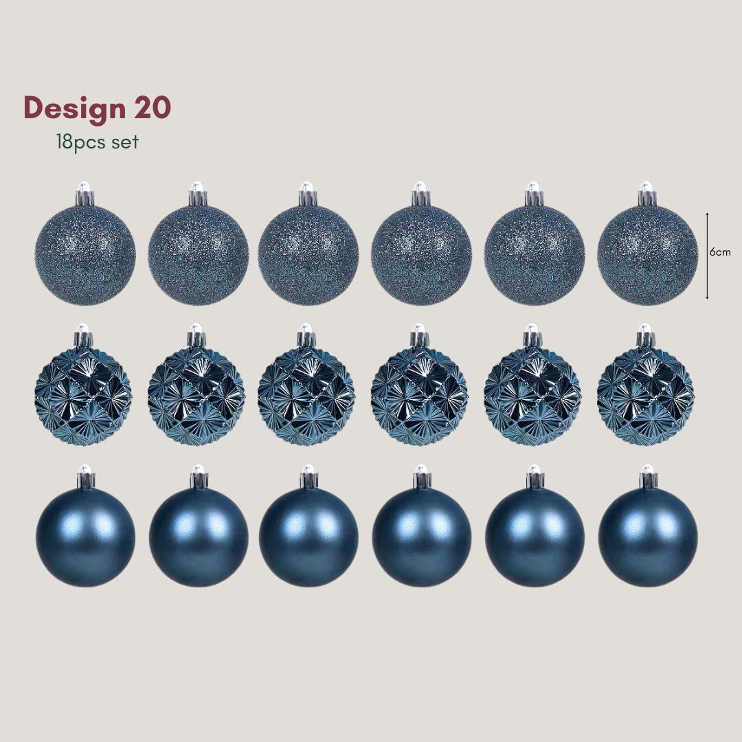 Yuletide Sparkle navy blue 6cm Christmas baubles featuring glitter, satin and geometric starburst designs hanging on a warm-lit artificial Christmas tree.